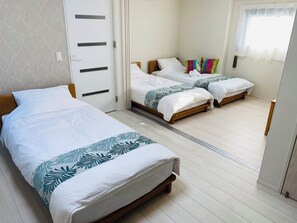 A hotel room with a single bed, a double bed, and a wooden wardrobe.