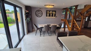 Una cocina moderna con comedor, ventanas amplias y una escalera.