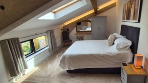 Un dormitorio con tragaluz, una cama, un escritorio, una silla y un armario.