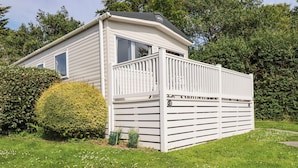 Ein Bungalow mit umzäunter Terrasse, umgeben von viel Grün.