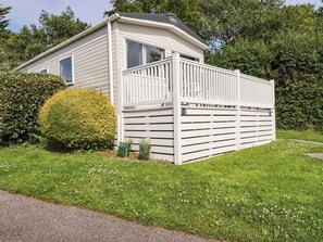 Ein Bungalow mit umzäunter Terrasse, umgeben von viel Grün.