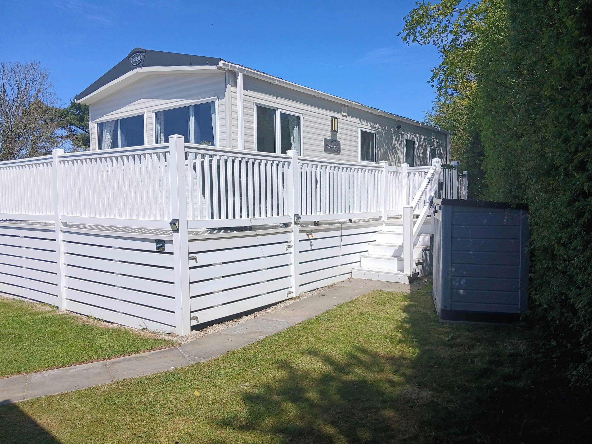 A mobile home with a white exterior, a covered porch, and a small attached garage.