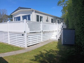A mobile home with a white exterior, a covered porch, and a small attached garage. - Porthcurno 5 (Truro)
