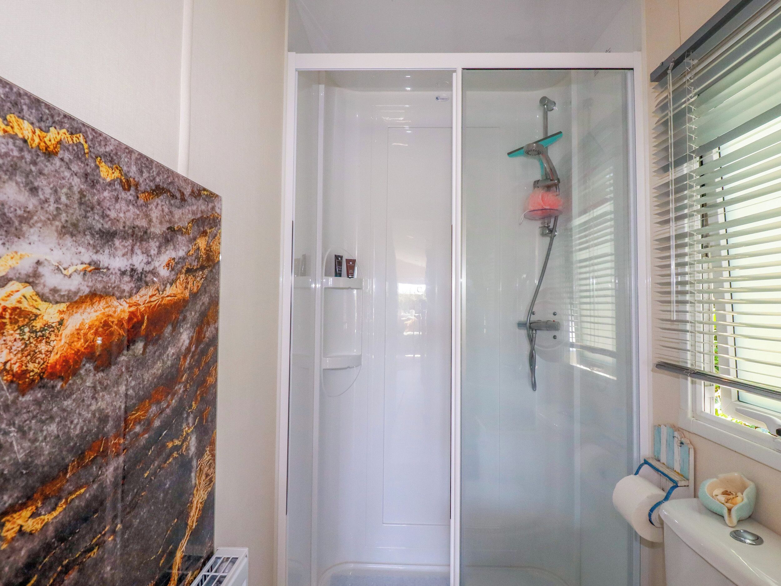 Ein Badezimmer mit einer Duschkabine aus Glas, einer Toilette und einer Marmorwand.