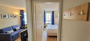 Ein Hotelzimmer mit einem Bett, einem Schlafsofa, einem Schreibtisch mit Computer und einem hölzernen Wandregal.