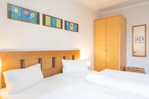 A hotel room with a wooden headboard, a large wardrobe, and wall art. - Moderne Ferienwohnung mit Balkon Strandnah im Seepark Sellin (Sellin)
