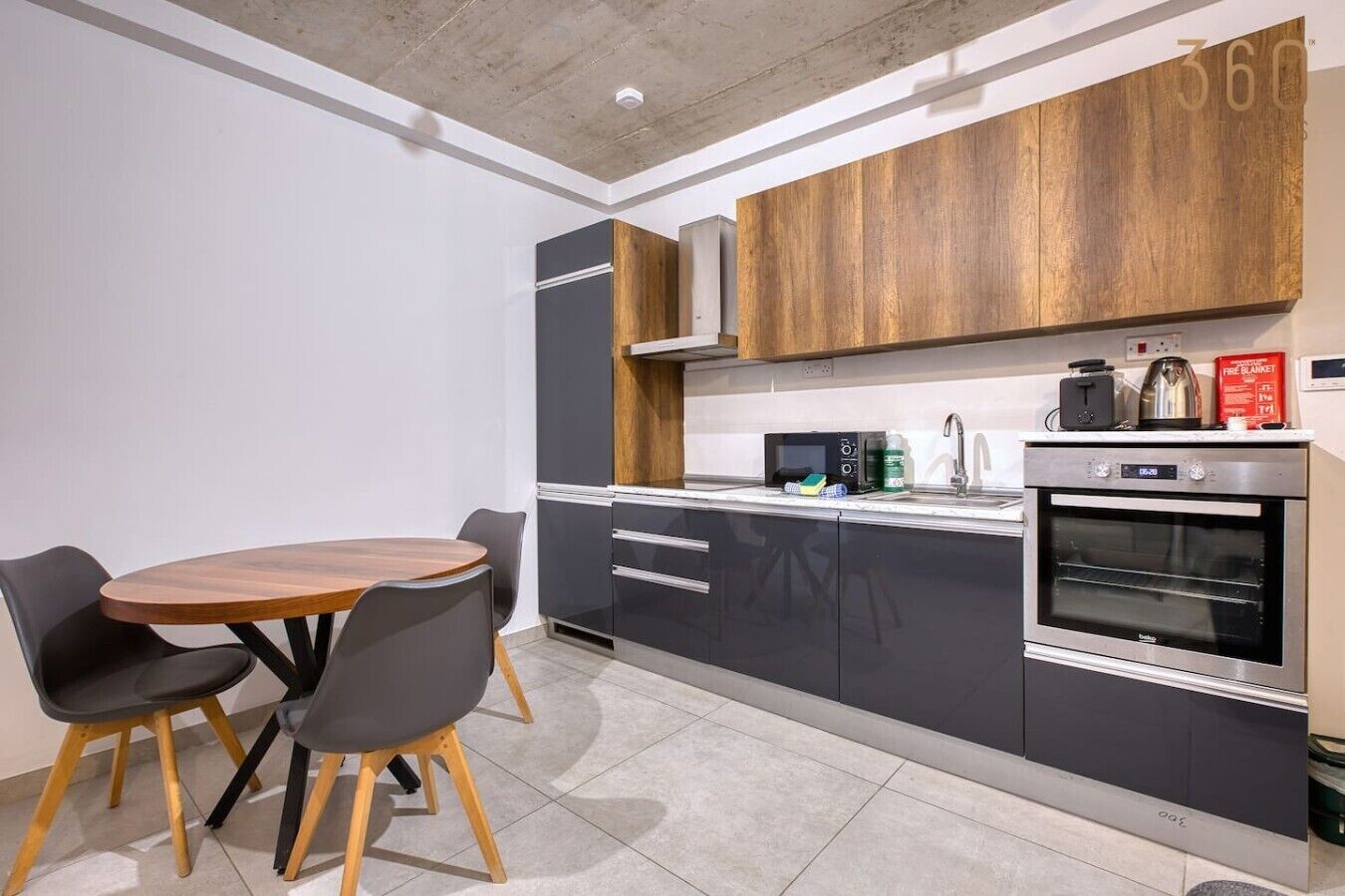 A modern kitchen with a dining table and chairs, built-in appliances, and a wooden accent wall.