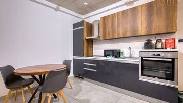 A modern kitchen with a dining table and chairs, built-in appliances, and a wooden accent wall.