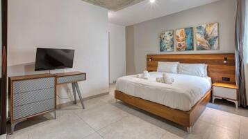 A bedroom with a bed, a TV, and artwork on the wall.