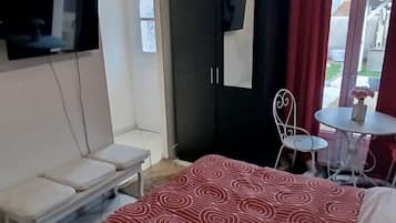 Ein Schlafzimmer mit einem Bett, einem Fernseher, einem Kleiderschrank, einem kleinen Tisch und einem Sessel.