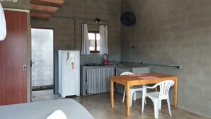 Una cocina compacta con refrigerador, estufa a gas y una mesa de comedor con sillas.