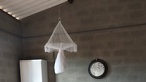 Un dormitorio con cama, armario, una pequeña mesa con una planta y un adorno en la pared.