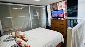 Une chambre moderne avec un lit, une télévision, un bureau et un balcon.
