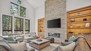 Una sala de estar moderna con chimenea, ventanas amplias y un televisor de pantalla plana.