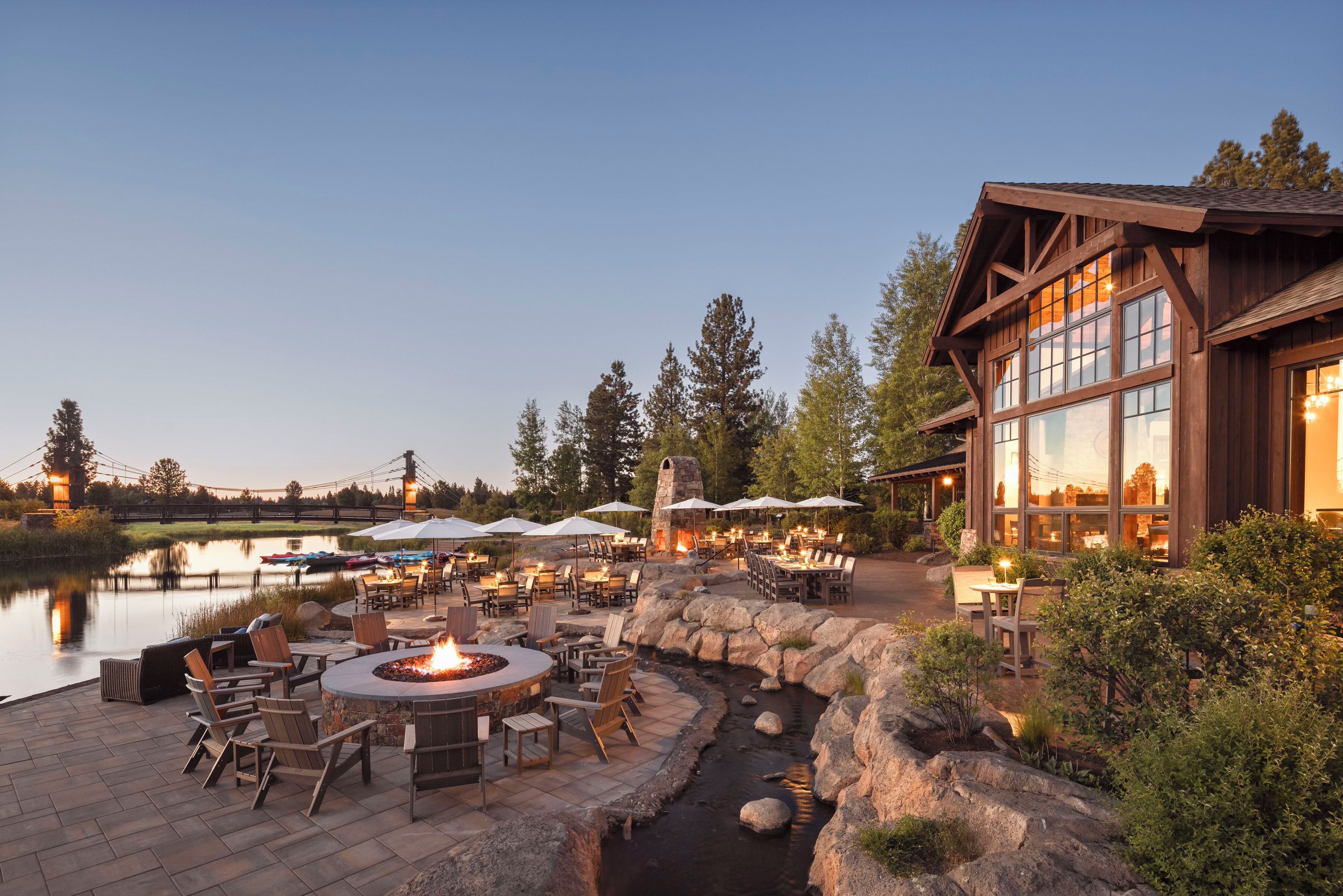 An outdoor patio area with a fire pit, seating, and a view of a lake.