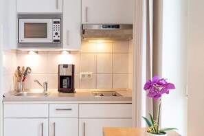 A kitchen with white cabinets, a microwave, a coffee maker, and a sink. - Komfortable Ferienwohnung fur Zwei in Sellin mit Balkon (Sellin)