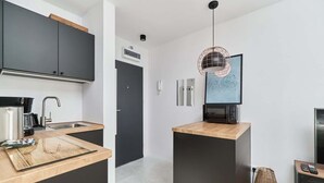 Eine moderne Küche mit schwarzen Schränken, einer Holztischplatte, einer eingebauten Mikrowelle und einer Pendelleuchte.