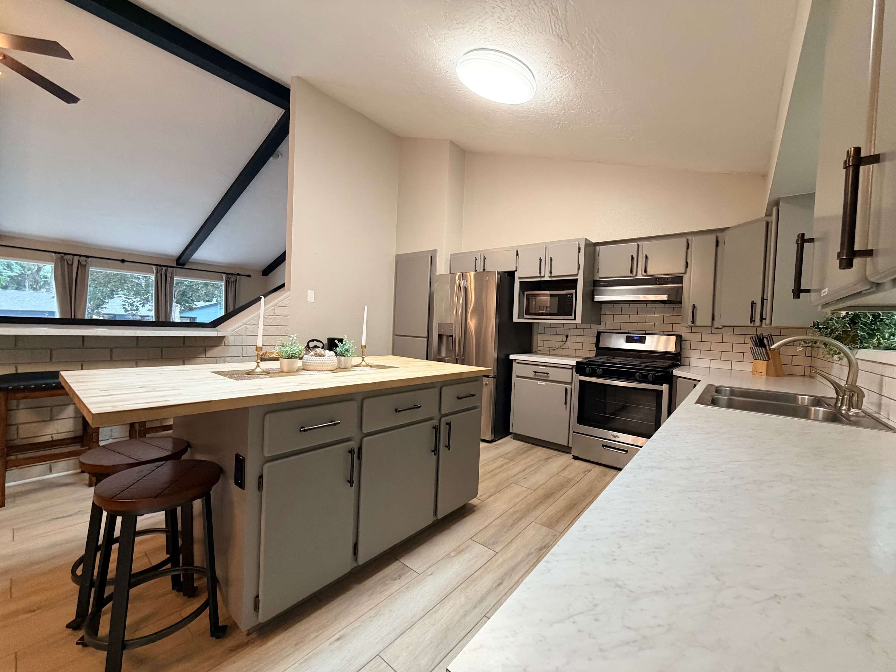 Uma cozinha moderna com uma ilha grande, eletrodomésticos de aço inoxidável e uma janela com vista para um jardim.