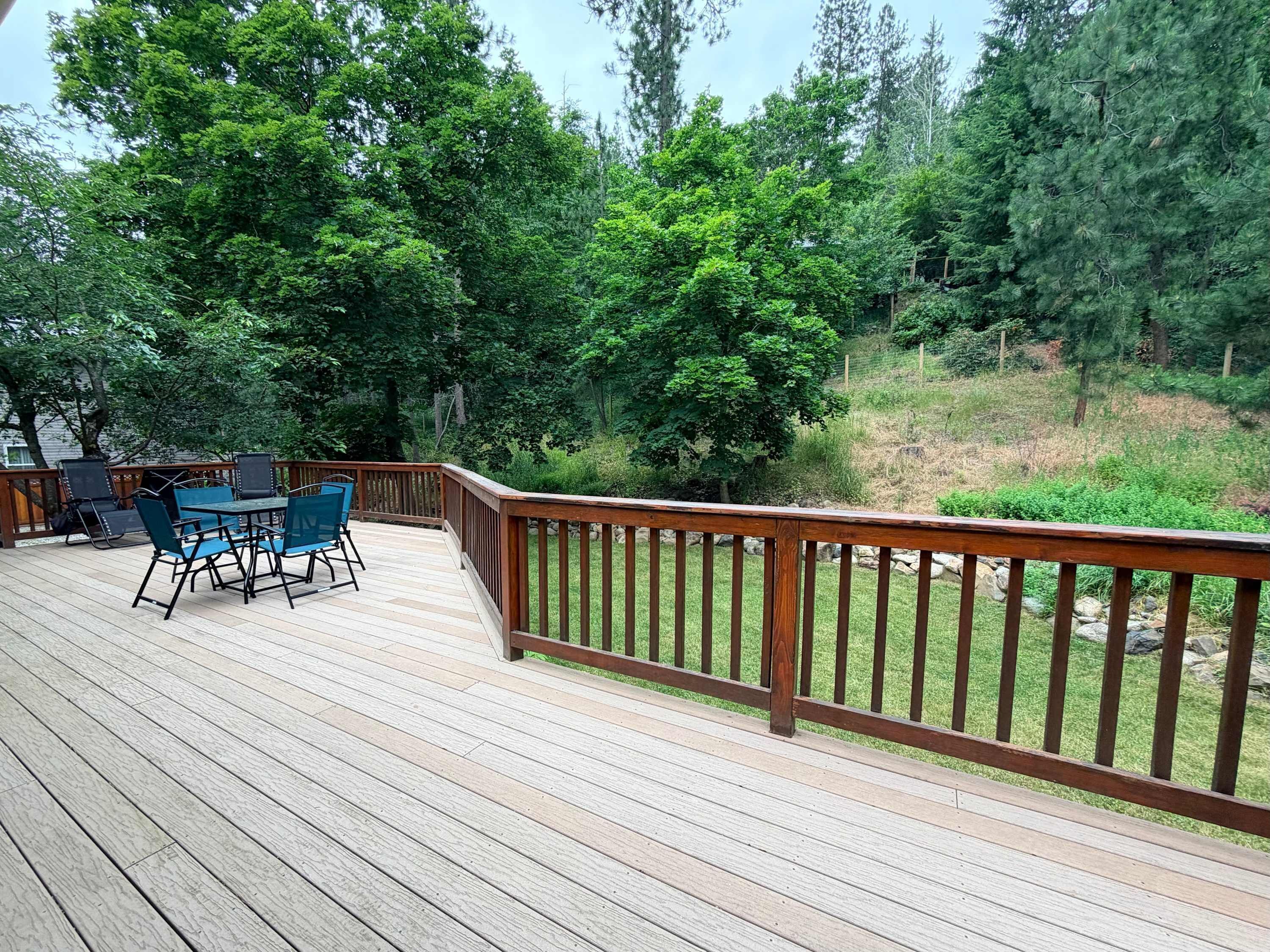 Une terrasse en bois avec une table et des chaises, entourée d’une végétation luxuriante.