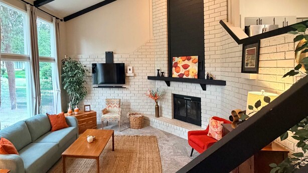 A living room with a fireplace, a sofa, a coffee table, and a staircase. - Fernan Retreat 3BR Minutes to Downtown the Lake (Coeur d'Alene)