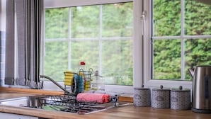 Eine Küche mit Fenster, Spüle, Geschirrgestell, Teedosen und Wasserkocher.