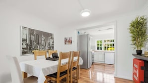Ein Essbereich mit Tisch und Stühlen, ein Kühlschrank und eine Küche im Hintergrund.