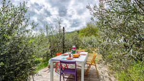 Un espacio exterior para comer con una mesa preparada para dos personas, rodeado de vegetación natural.
