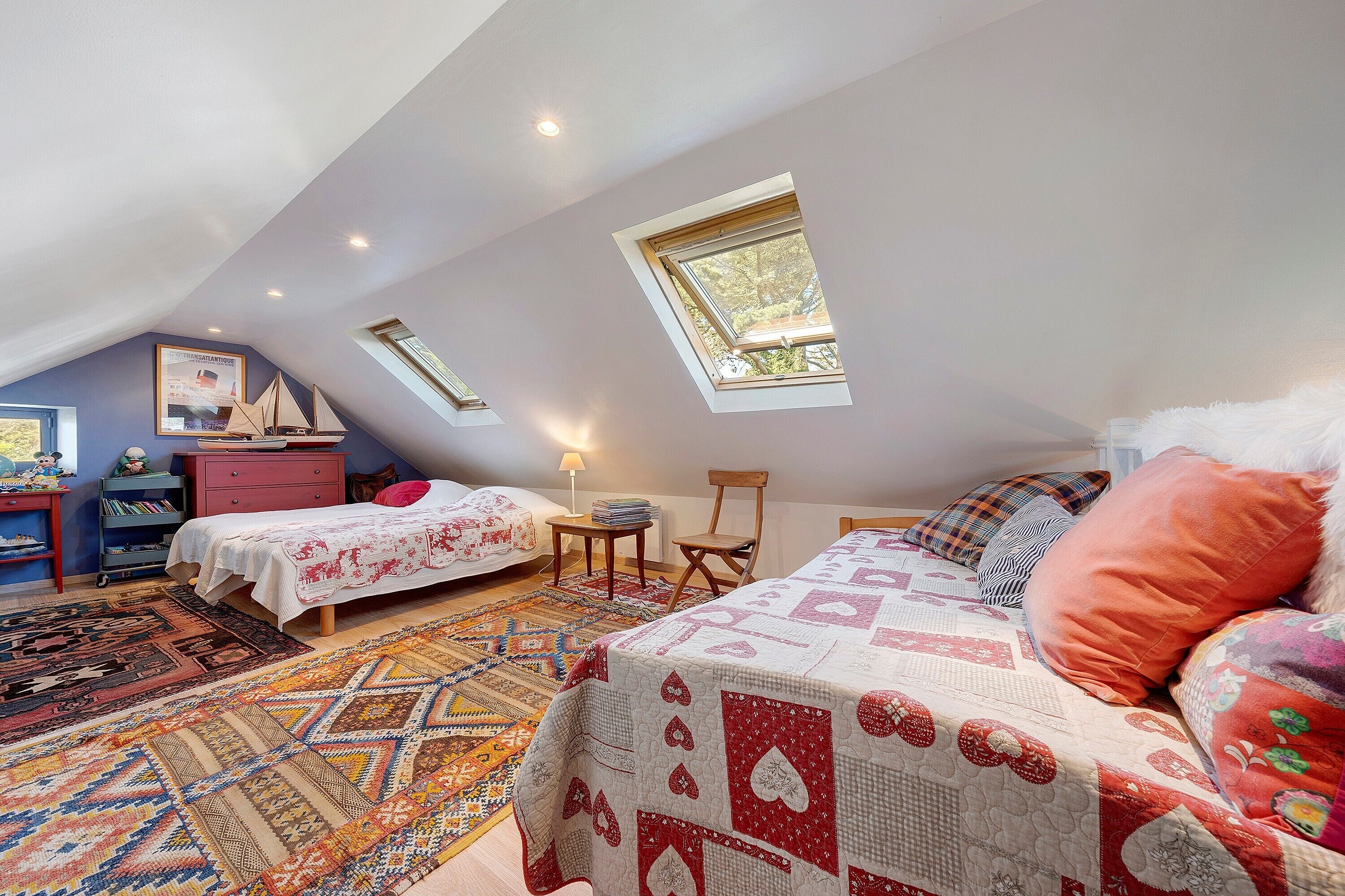 Une chambre avec deux lits, un bureau, une chaise et une fenêtre.