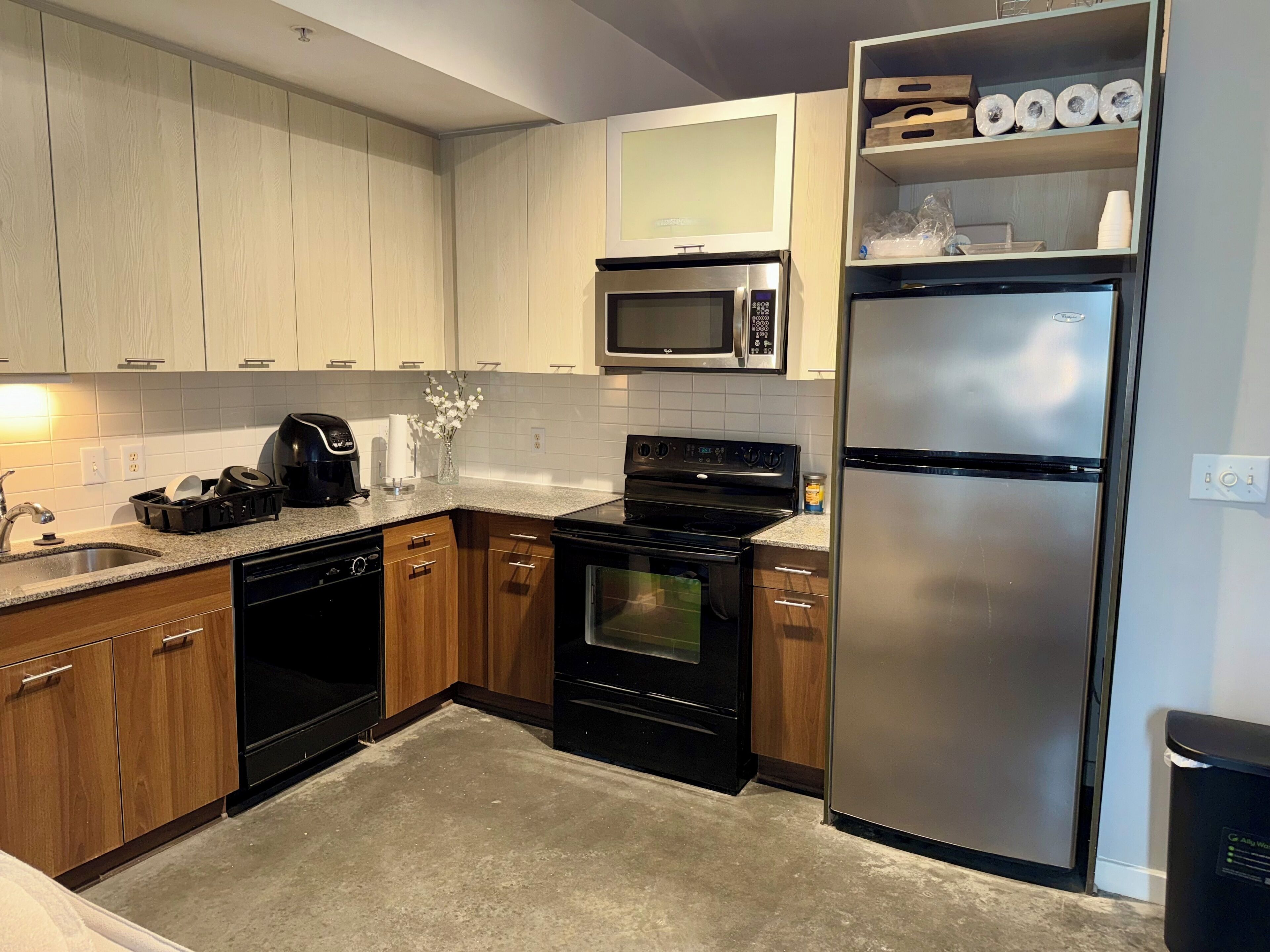 A modern kitchen with wooden cabinets, a stainless steel refrigerator, a microwave, a stove, and a dishwasher.