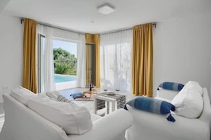 A modern living room with a sofa, a coffee table, and a view of an outdoor swimming pool.
