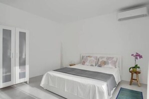 Ein Schlafzimmer mit Bett, Kleiderschrank, Nachttisch und einer Topfpflanze.