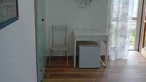 A room with a TV mounted on the wall, a desk, a chair, and a small cabinet. - Cuore Verde del Cilento (Laureana Cilento)