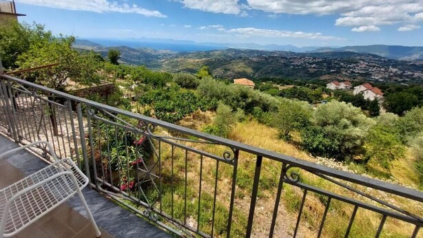 A balcony with a metal railing overlooking a landscape with trees and distant buildings. - Cuore Verde del Cilento (Laureana Cilento)
