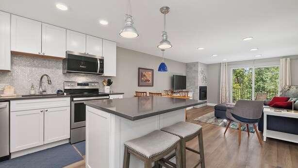 A modern kitchen with white cabinets, stainless steel appliances, and a central island with bar stools. - Beaver Village Unit #0613 Renovated 1 bed 1st floor private patio washer dryer (Winter Park)
