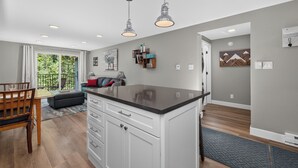 A modern kitchen with white cabinetry, a black countertop, pendant lighting, and a view to a balcony. - Beaver Village Unit #0613 Renovated 1 bed 1st floor private patio washer dryer (Winter Park)