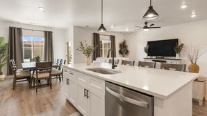 Una cucina moderna con isola centrale, mobili bianchi e lavastoviglie integrata.