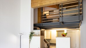 Ein modernes Interieur mit einer offenen Küchenzeile im Loft-Stil, einer Treppe und einem Sofa mit Decke.