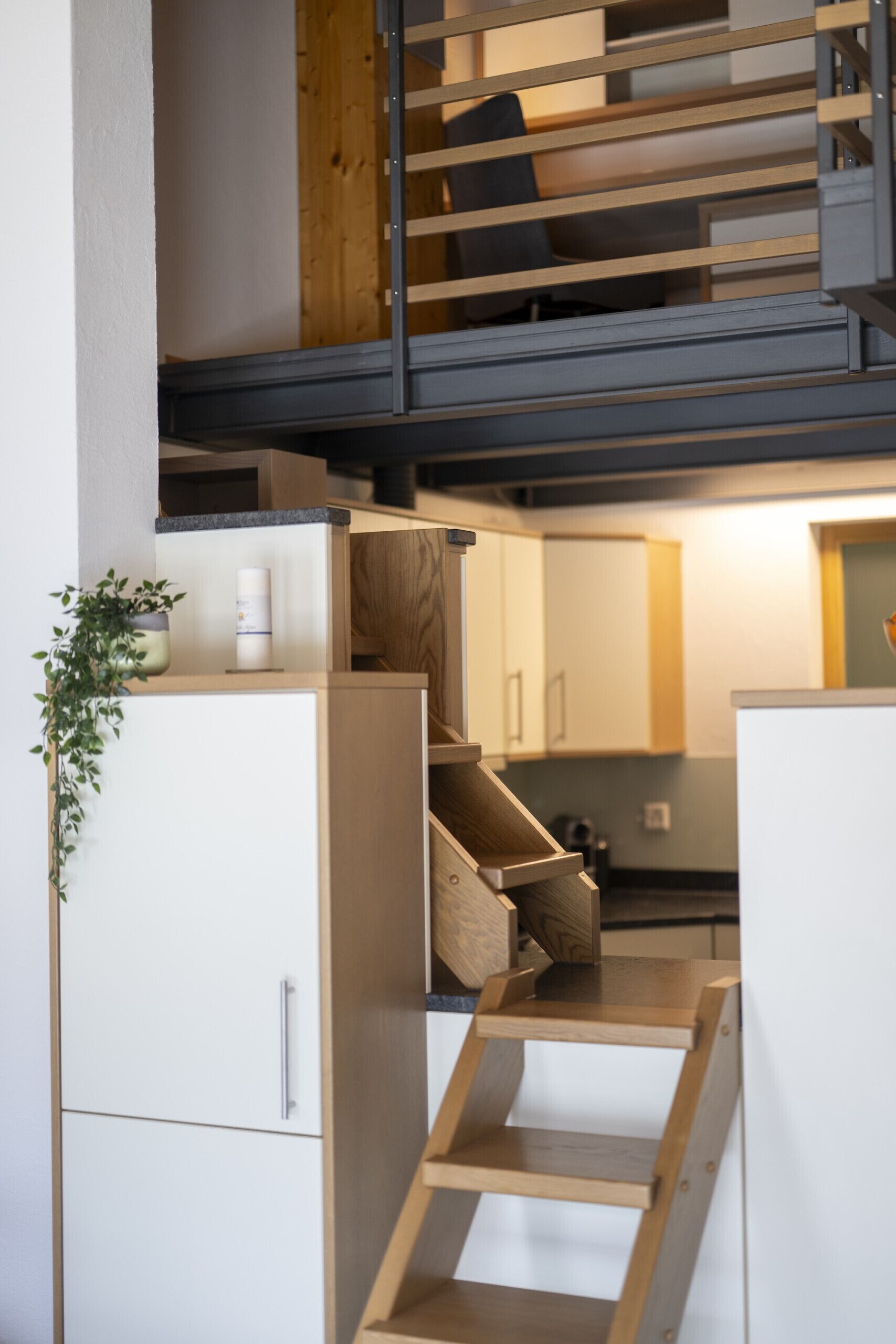 Une cuisine moderne avec des meubles en bois, un banc intégré et un escalier menant à un niveau supérieur.