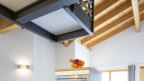 Eine Küche mit integrierten Geräten, ein Essbereich mit Tisch und Stühlen sowie ein Holzbalkendeckenbau.