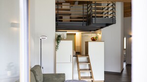 Ein modernes Interieur mit Holzboden, einer Couch, einem kleinen Tisch und einer Treppe, die zu einer oberen Ebene führt.