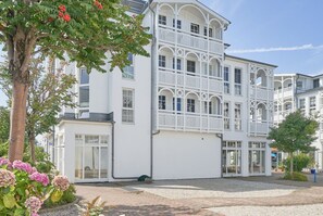 A multi-story building with balconies, large windows, and a gravel driveway. - Moderne Ferienwohnung im Seepark Sellin mit Balkon (Sellin)