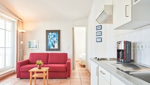 A modern kitchen with white cabinets, a coffee maker, and a countertop. - Moderne Ferienwohnung im Seepark Sellin mit Balkon (Sellin)