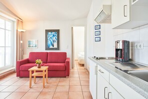 A modern kitchen with white cabinets, a coffee maker, and a countertop. - Moderne Ferienwohnung im Seepark Sellin mit Balkon (Sellin)