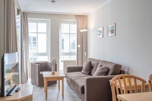 A modern living room with a sofa, a coffee table, a TV, and a lamp. - Ostseeurlaub Ferienwohnung mit Balkon in Sellin (Sellin)