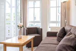 A modern living room with a sofa, a table, and a vase of flowers. - Ostseeurlaub Ferienwohnung mit Balkon in Sellin (Sellin)