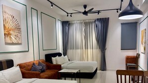 Ein modernes Hotelzimmer mit einem großen Bett, einer Couch, einem Esstisch und einem Deckenventilator.
