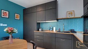 Uma cozinha moderna com armários escuros, painel de backsplash em padrão herringbone e uma mesa de jantar de madeira.