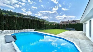 A swimming pool with a clear blue sky and a view of a house in the background.