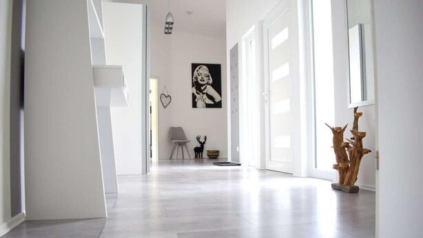A modern hallway with a minimalist design, featuring a light-colored floor and white walls.