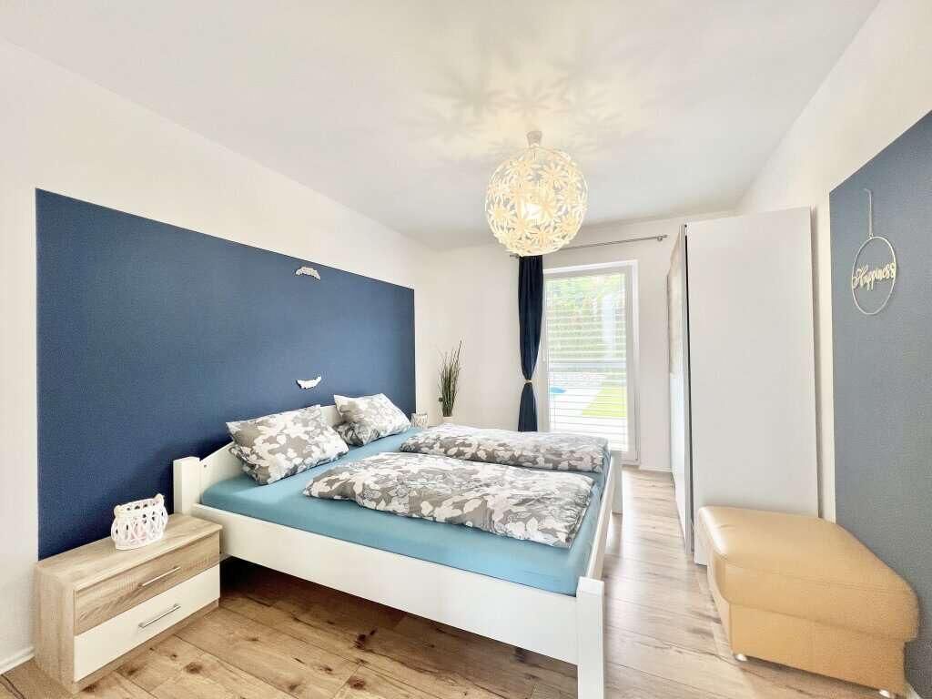 A bedroom with a bed, bedside table, and a hanging light fixture.